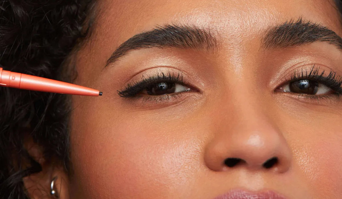  Woman applying sketch eyeliner using easy eyeliner hacks for everyday makeup.